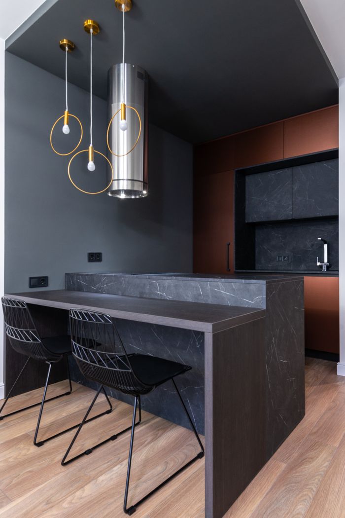 Contemporary kitchen with stylish pendant lights, marble countertop, and minimalist chairs.